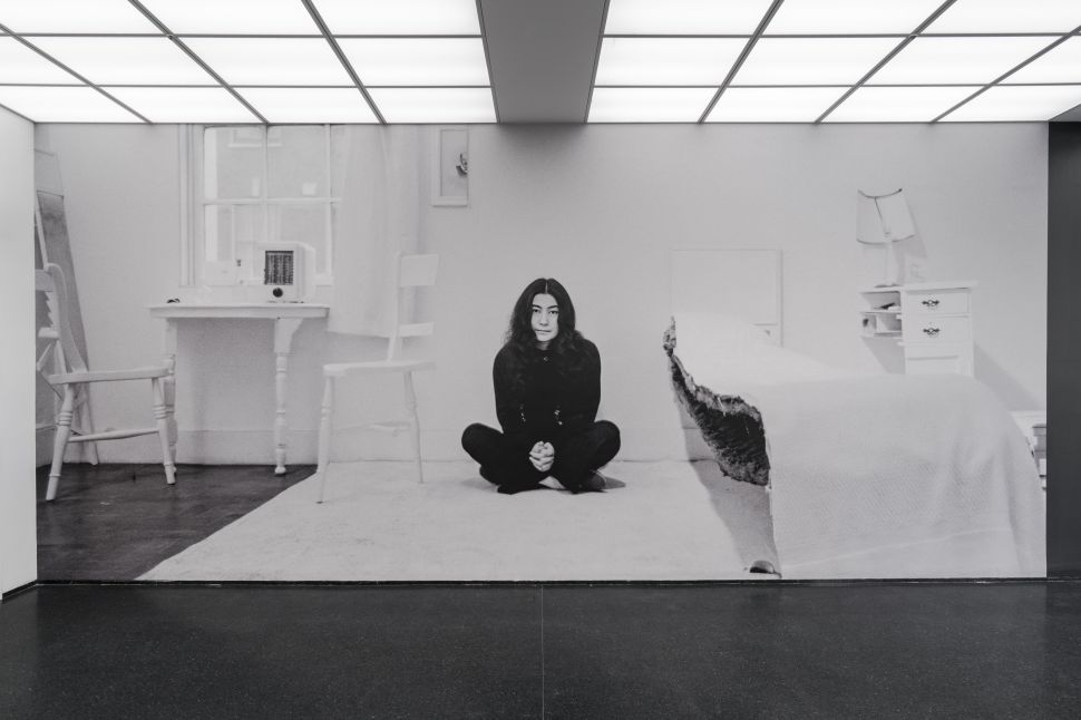 A black and white photo of an asian woman sitting in a museum installation
