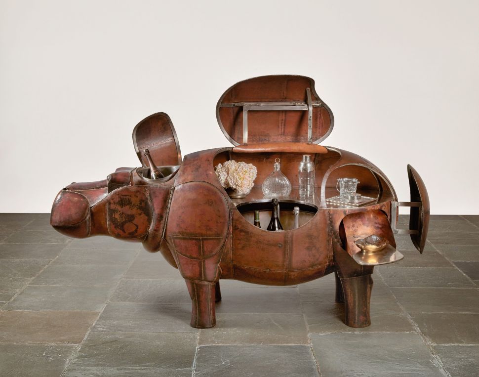 A bar cart shaped like a hippo, with several panels open to reveal the compartments holding bottles and glassware