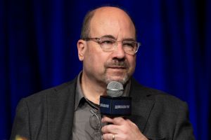 Man in blazer speaks into microphone